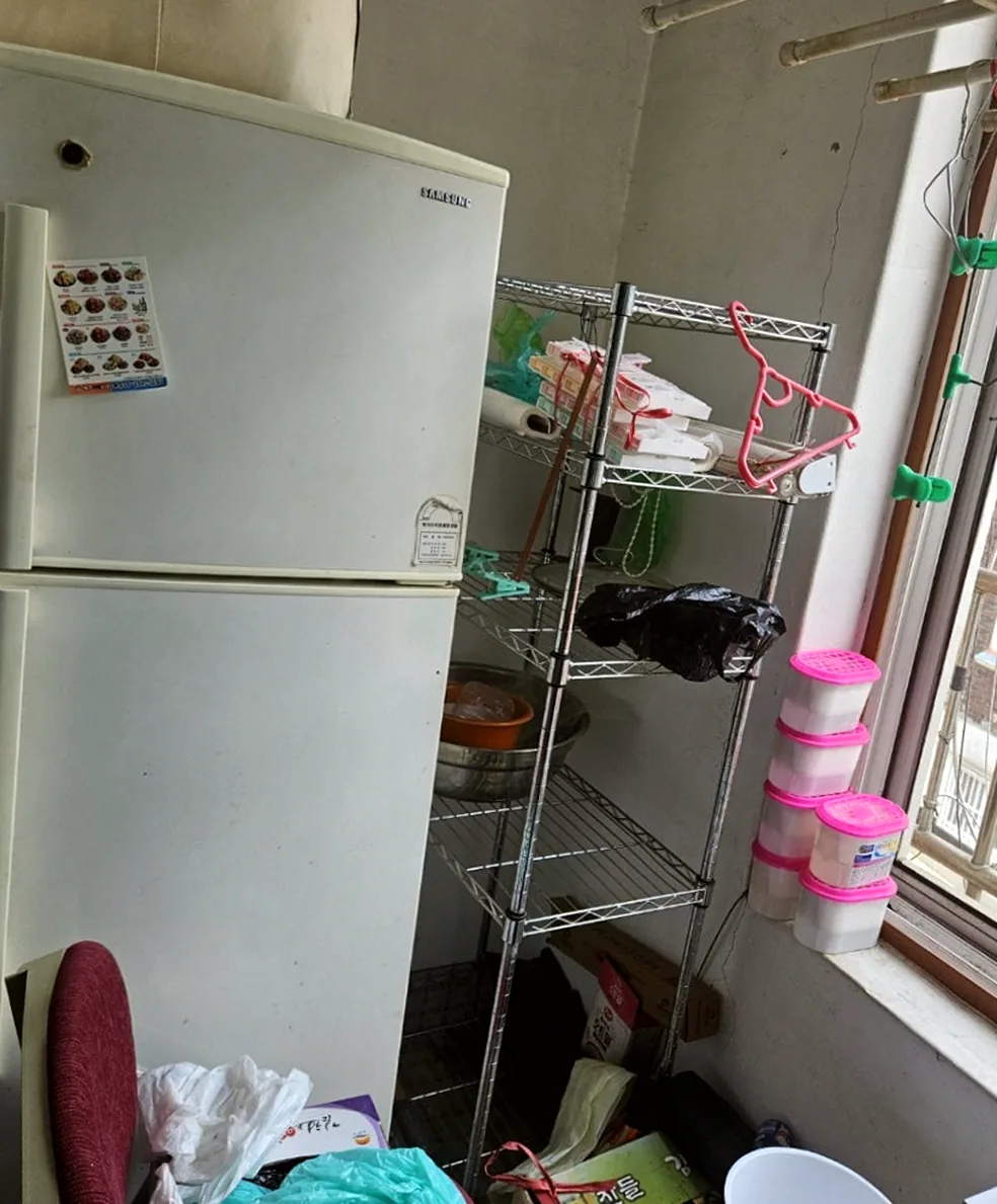 정리 전 앞베란다 — 2도어 냉장고와 철제 선반, 창턱의 분홍 제습제 통