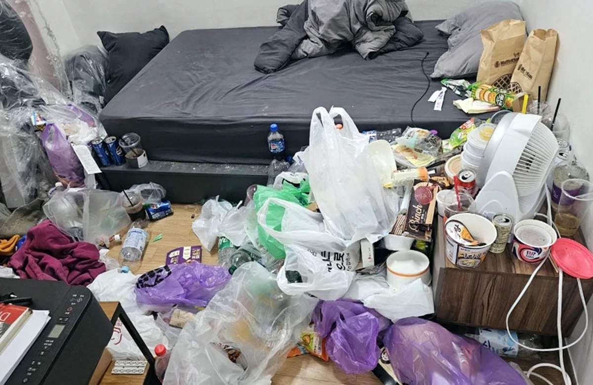 정리 전 침실 — 바닥을 덮은 비닐봉지와 맥주캔, 협탁 위 먹다 남은 컵과 아이스크림 통