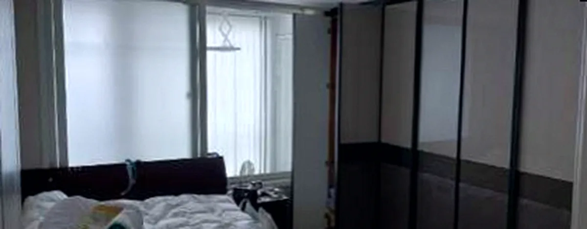 정리 전 침대방 — 흰 이불과 베개가 흐트러진 큰 침대와 붙박이장