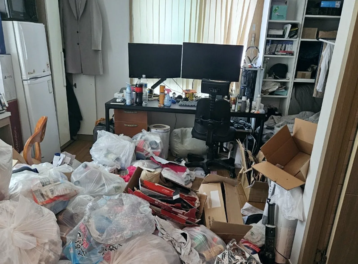 인천 청라동 오피스텔 책상 쪽 — 바닥을 덮은 쓰레기봉투를 치우고 원목무늬 장판이 드러남 — 작업 전