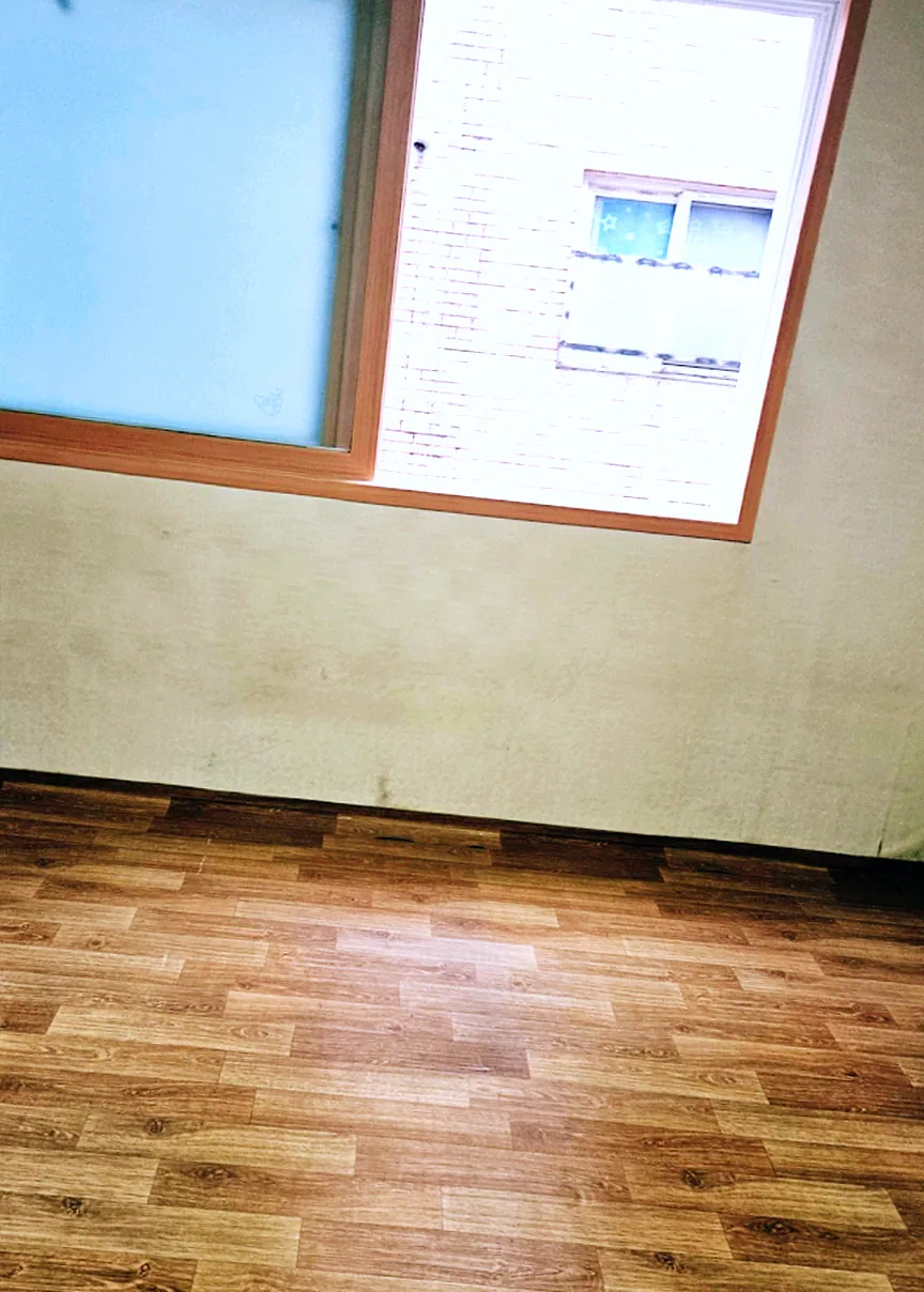 장롱과 서랍장을 분해해 내보낸 뒤 비워진 안방 — 벽지 아래쪽 변색