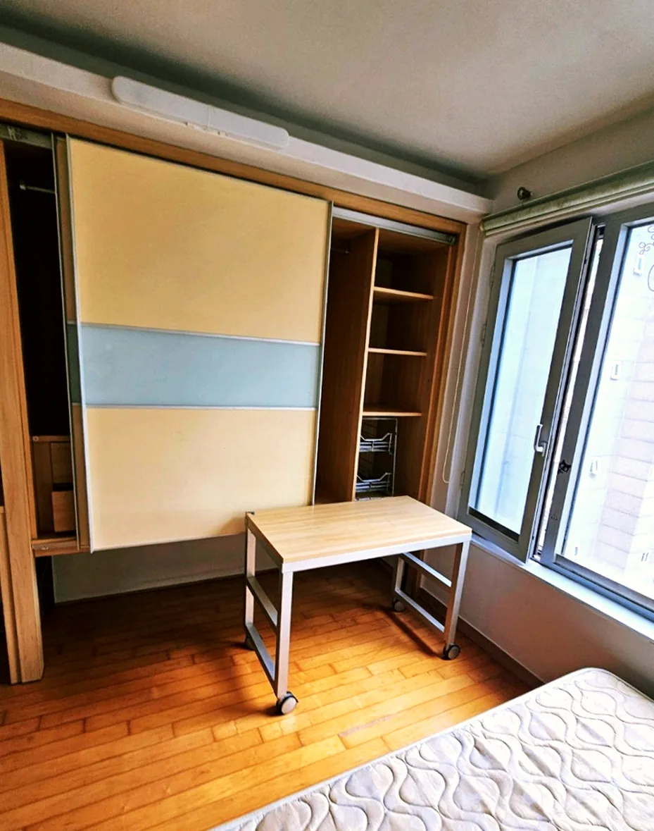 정리 후 방 — 슬라이딩 붙박이장과 선반장, 창가 테이블, 빌트인 매트리스만 남은 모습