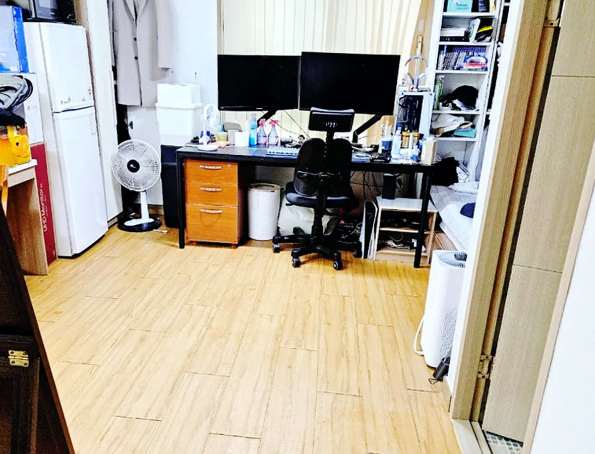 인천 청라동 오피스텔 책상 쪽 — 바닥을 덮은 쓰레기봉투를 치우고 원목무늬 장판이 드러남 — 작업 후