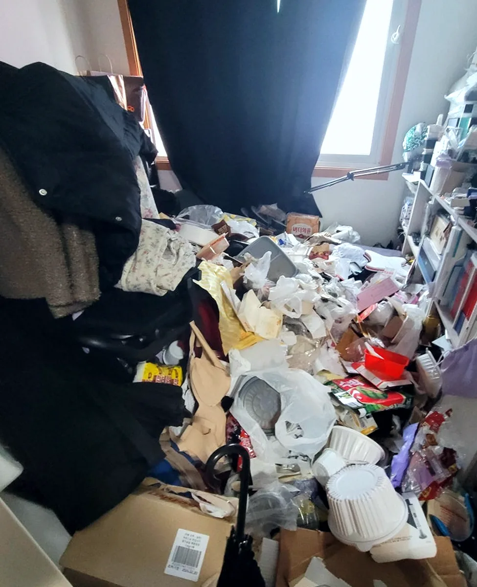 쓰레기집 청소 전 침실 — 잠자리 주변까지 밀려든 옷과 쓰레기