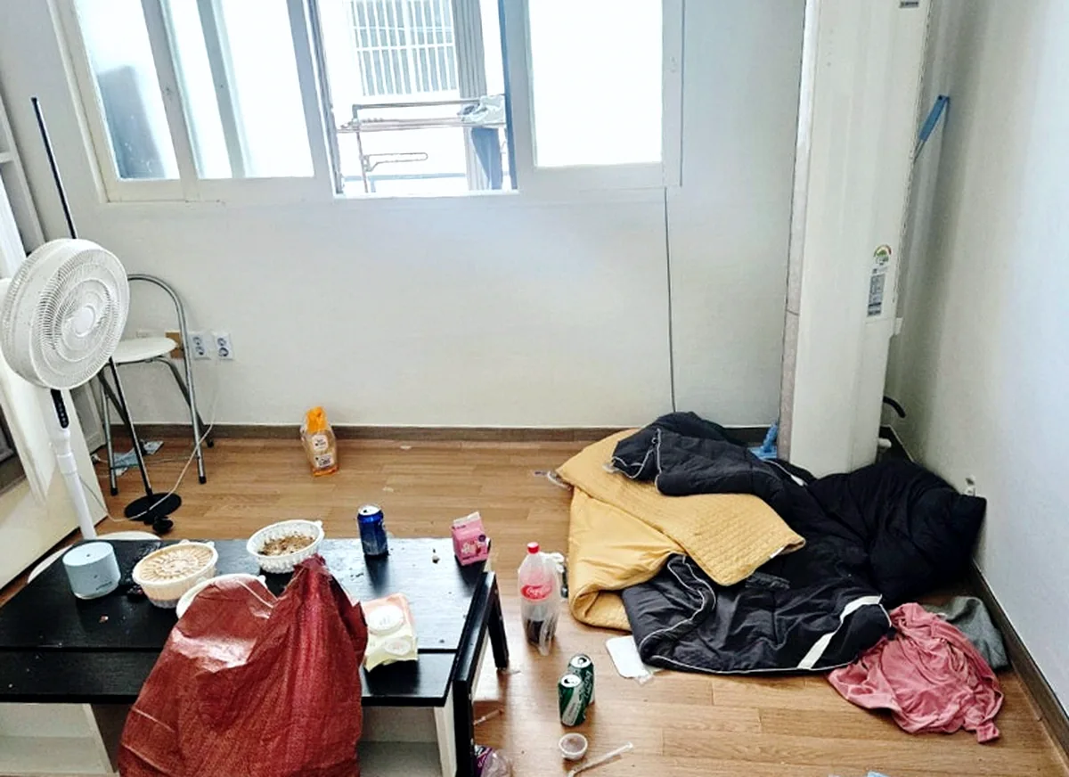 서울 화곡동 빌라 거실 창 쪽 — 이불·패딩 더미와 빈 캔을 치운 모습 — 작업 전